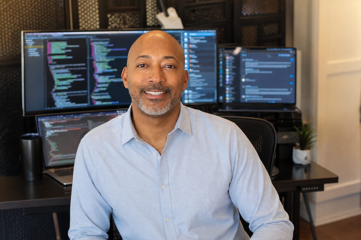 Jathan Desir at his desk, code on the monitors behind him